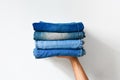 Close up stack of folded denim blue jeans in hand over white color wall background Royalty Free Stock Photo