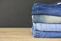 Close up stack of folded denim blue jeans on wooden table with black color wall background, copy space Royalty Free Stock Photo