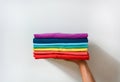 Close up stack of folded multicolored t-shirt in hand over white background, copy space Royalty Free Stock Photo