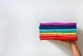 Close up stack of folded multicolored t-shirt in hand over white background, copy space Royalty Free Stock Photo
