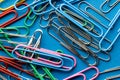 Close up of stack of multi coloured paper clips on blue background