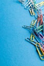 Close up of stack of multi coloured paper clips and copy space on blue background