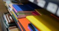 Close-up of stack of multicolored notebooks and exercise books on shelf in shop.