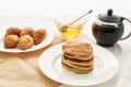 Close up of a stack of sweet tasty pancakes, croissants, honey in a bowl with dipper and a teapot, Breakfast served on