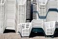 Stack of white and green plastic empty chairs on beach . Beginning or ending the summer season