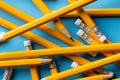 Close up of stack of yellow pencils with erasers on blue background