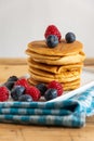 Close-up of stacked pancakes with blueberries and raspberries on blue cloth Royalty Free Stock Photo