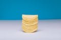 Close-up of stacked potato chips on table against blue background with copy space