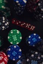 Close up stacks of different colored poker chips and playing dices on the casino table isolated over black background. Gambling Royalty Free Stock Photo