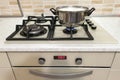 Close-up of stainless steel cooking pot on gas stove in contemporary upscale modern home kitchen. Selective focus on pot. Royalty Free Stock Photo