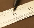 Close-up of a stainless steel scale ruler showing an eleven-inch point with a pen, Selective focus, isolated on Dark background Royalty Free Stock Photo