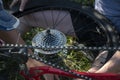 Close up, the star of the chain of switching speeds of a mountain bike and a removed wheel in the hand of a person, a cyclist Royalty Free Stock Photo