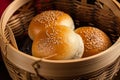 Close-up of steamed BBQ pork buns with sesame seeds on a bamboo basket