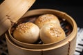 Close-up of steamed BBQ pork buns with sesame seeds on a bamboo basket