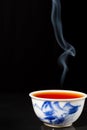 Close-up of steaming blue and white china tea cup, black background, vertical Royalty Free Stock Photo