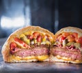 Close-up of a steaming meat and vegetable Muffuletta sandwich cut in half