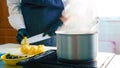 Close-up of a steaming saucepan on a stove when chef cleans a lemon