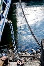 Close-up of a Steel Chain of a bridge on the blue water of the river Rhein in Cologne with big stones at the coast Royalty Free Stock Photo