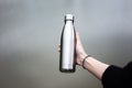 Close-up of steel thermo bottle in hand of young girl.