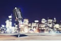 Close up of steel vintage singing vocal microphone on wooden surface and blurry night city backdrop.