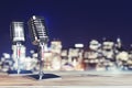 Close up of steel vintage singing vocal microphones on wooden surface and blurry night city backdrop.