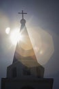 Close up a steeple of the church with a sun at background,intentionally take with lens flare effect,silhouette church