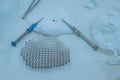Close-up of a sterile operating table with medical neurosurgical instruments, including a titanium plate, a mesh for the skull,