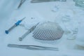 Close-up of a sterile operating table with medical neurosurgical instruments, including a titanium plate, a mesh for the skull,