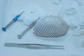Close-up of a sterile operating table with medical neurosurgical instruments, including a titanium plate, a mesh for the skull,