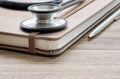 Stethoscope and brown diary on wooden table