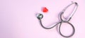 Close up Stethoscope and red heart on pale pink isolated background with copy space for text. Close up, top view. Medical equipme