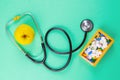 Close-up stethoscope and yellow apple on light green background with pills in wooden box. Top views Royalty Free Stock Photo