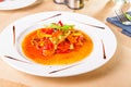 Close up stew fish fillet with vegetables decorated with basil leaf on the white plate on the served woodan table. healthy food,