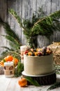 Close up. New Year`s Cake, decorated blueberries, strawberries, kumquat. Nearby are orange tangerines, burning festive candles Royalty Free Stock Photo