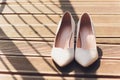 Close Up Still Life of Pair of Plain White Bridal Shoes with High Heels Resting on Rustic Wooden Floor or Table with