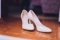 Close Up Still Life of Pair of Plain White Bridal Shoes with High Heels Resting on Rustic Wooden Floor or Table with