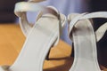 Close Up Still Life of Pair of Plain White Bridal Shoes with High Heels Resting on Rustic Wooden Floor or Table with