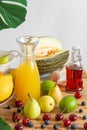 Close up of still life with summer fruits, bottle with orange juice and blueberries, on wooden table and white background Royalty Free Stock Photo