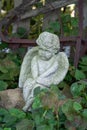 Angel cupid stone statue sitting in garden