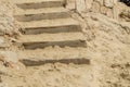 Close-up of stone stairs and sand on the Mediterranean beach, background footprints in the sand