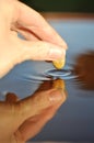 Close-up of stone touching water surface, creating ripple. Royalty Free Stock Photo