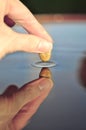 Close-up of stone touching water surface, creating ripple. Royalty Free Stock Photo