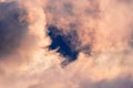 Close up of storm clouds colored in sunset colors; break in the clouds reveals dark blue sky Royalty Free Stock Photo