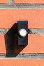 A close up straight portrait of a black and white old plastic doorbell on a red brick wall. The device is ready to be used for Royalty Free Stock Photo