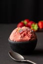 Close up of strawberry ice cream in bowl and black table with spoon Royalty Free Stock Photo