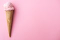 Close up strawberry ice cream in waffles cone against pink background. Copy space