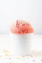 Close up of strawberry ice cream in white bowl on table and white background with wafer crumbs Royalty Free Stock Photo