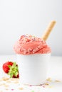 Close-up of strawberry ice cream in white cup with wafer on table and white background with crumbs Royalty Free Stock Photo