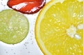 Close-up strawberry, lemon and green lemon slice in water with bubbles soda on white background Royalty Free Stock Photo