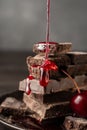 Close-up of strawberry syrup falling on pieces of chocolate on wooden table,